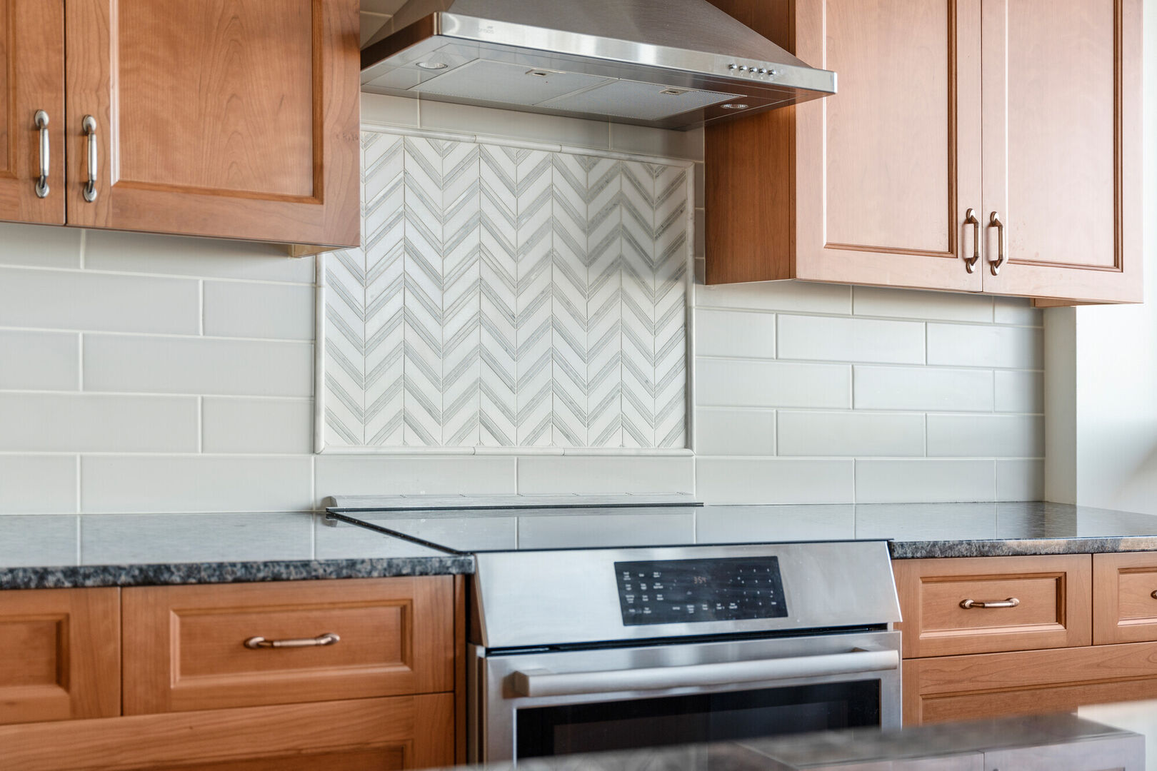 Kitchen backsplash accent tile above stove, white and grey marble chevron tile